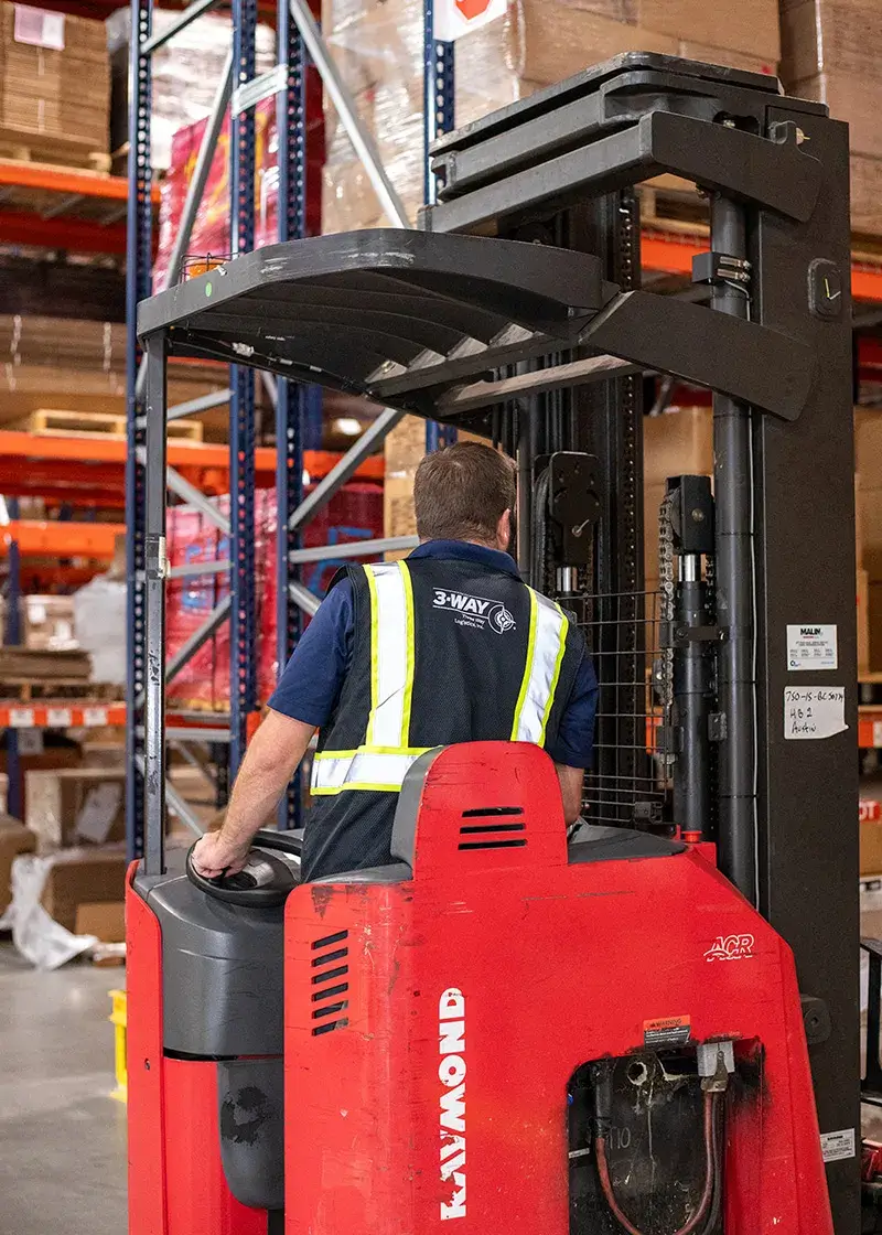 A Three Way Logistics warehouse employee driving a forklift