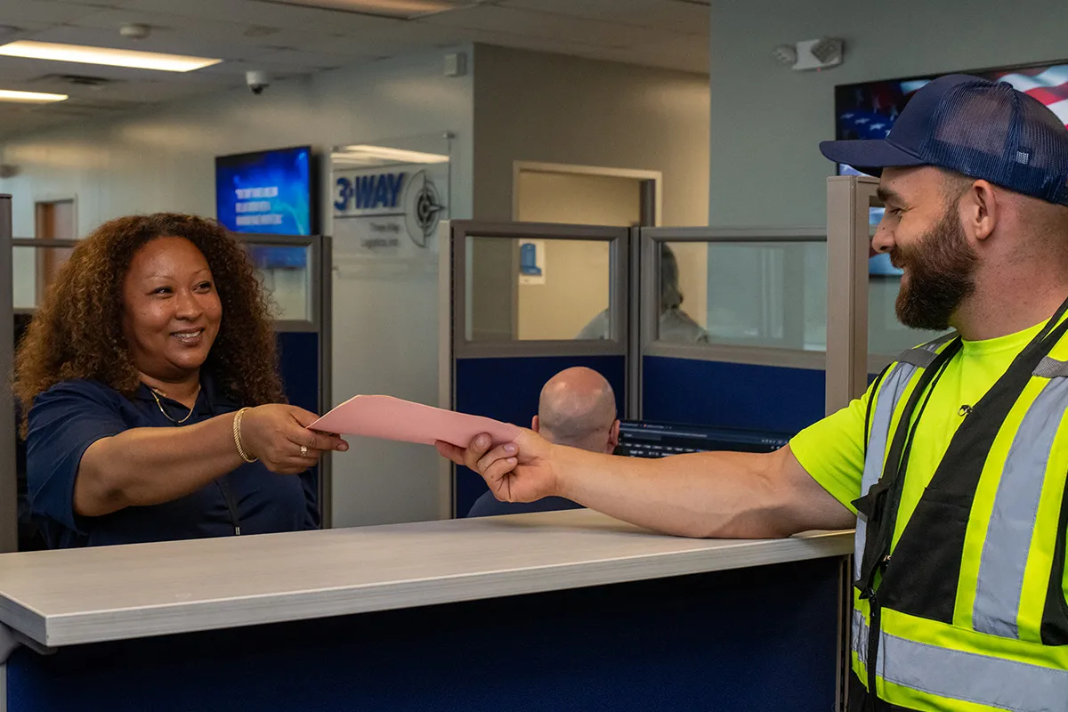 Why Are Trade Shows Important? - 3-WAY Two employees passing documents between each other