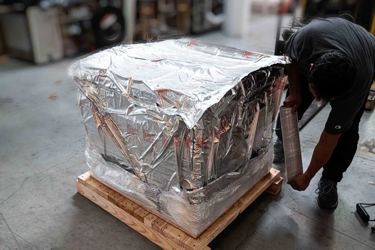 A warehouse worker wrapping a specialty crate in cling wrap