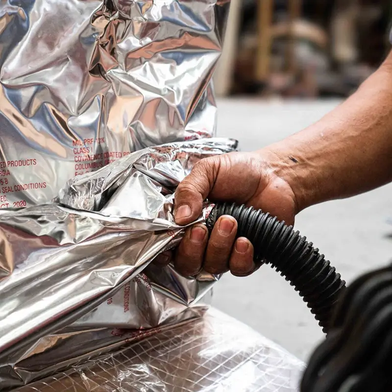 A warehouse worker vacuum-sealing a specialty crate shipment